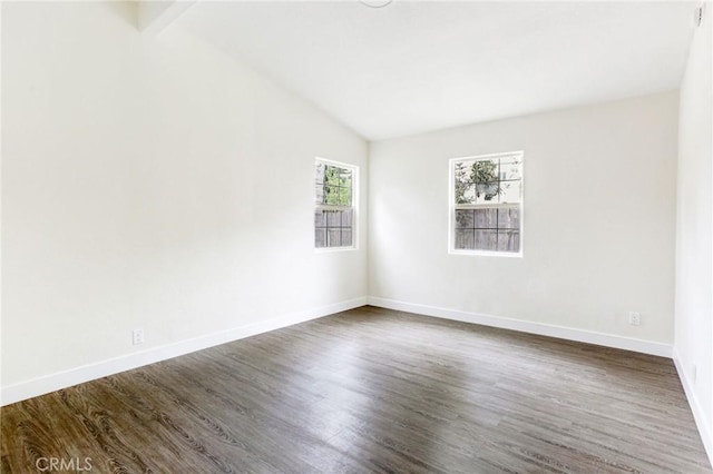 empty room featuring dark wood finished floors, vaulted ceiling, and baseboards