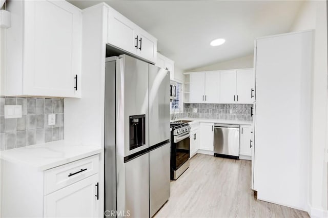 kitchen featuring vaulted ceiling, stainless steel appliances, tasteful backsplash, and light stone counters