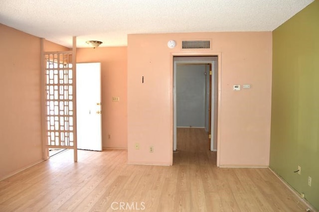 unfurnished room featuring light hardwood / wood-style floors and a textured ceiling