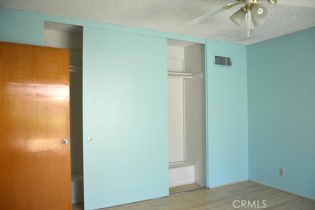 unfurnished bedroom featuring light hardwood / wood-style flooring, a textured ceiling, a closet, and ceiling fan