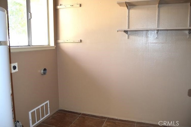 clothes washing area featuring hookup for an electric dryer and dark tile patterned floors