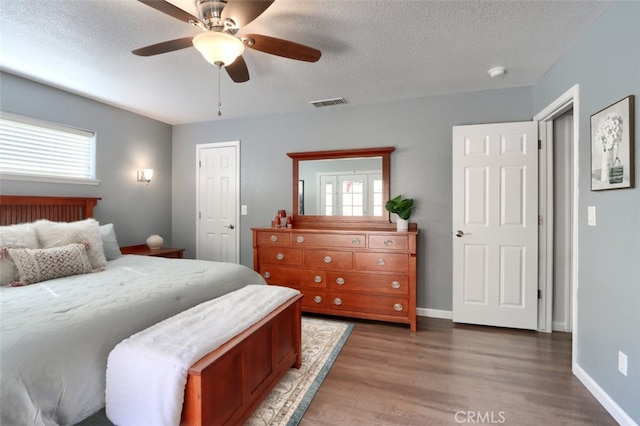 bedroom featuring a textured ceiling, dark hardwood / wood-style floors, and ceiling fan