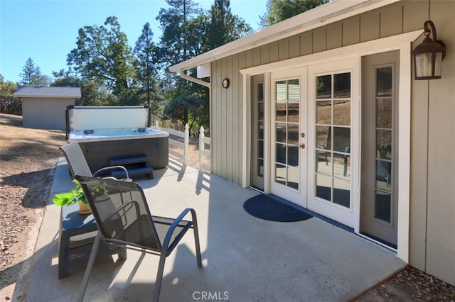 view of patio with french doors, a hot tub, and a storage shed