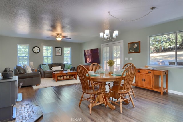 dining room with dark hardwood / wood-style flooring, a textured ceiling, ceiling fan with notable chandelier, and plenty of natural light