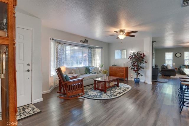 living room with a textured ceiling, dark wood-type flooring, and ceiling fan