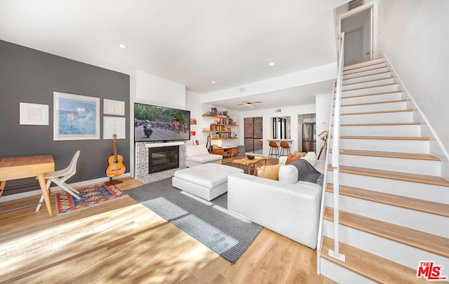 living room featuring wood-type flooring and a tiled fireplace