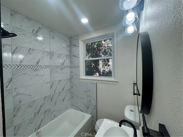 bathroom featuring tiled shower / bath combo and toilet