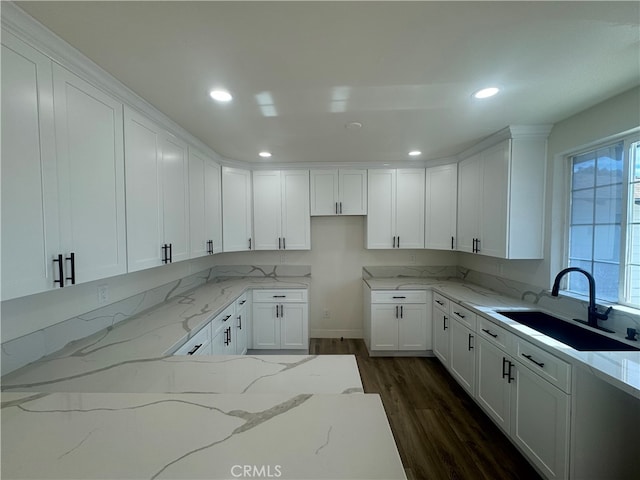 kitchen featuring dark wood-type flooring, light stone counters, sink, and white cabinets