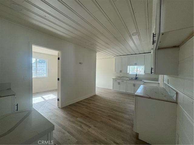 kitchen with white cabinetry, a healthy amount of sunlight, sink, and wood-type flooring