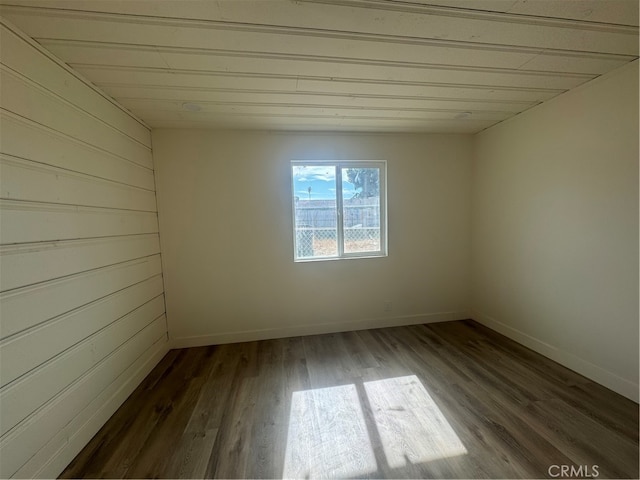 empty room featuring wooden walls and dark hardwood / wood-style flooring