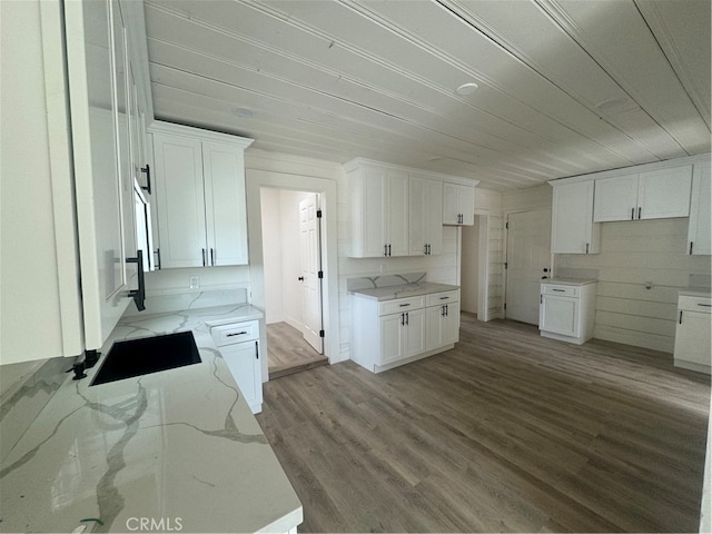 kitchen with white cabinets, light stone countertops, light wood-type flooring, and stovetop