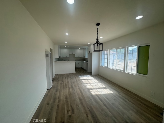 unfurnished living room featuring a chandelier and dark hardwood / wood-style flooring