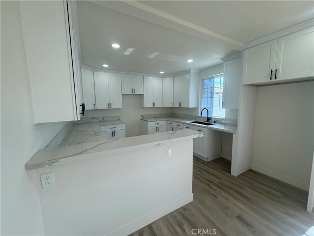 kitchen featuring hardwood / wood-style floors, sink, white cabinets, and light stone counters