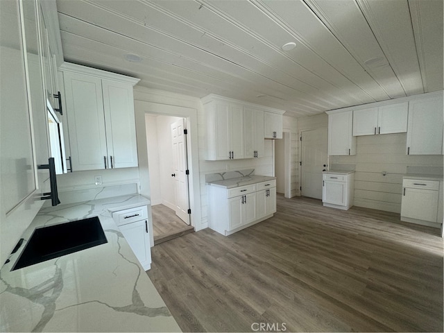 kitchen featuring white cabinetry, light stone countertops, and light hardwood / wood-style flooring