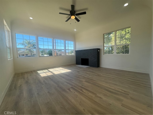 unfurnished living room with a brick fireplace, dark hardwood / wood-style floors, and a healthy amount of sunlight