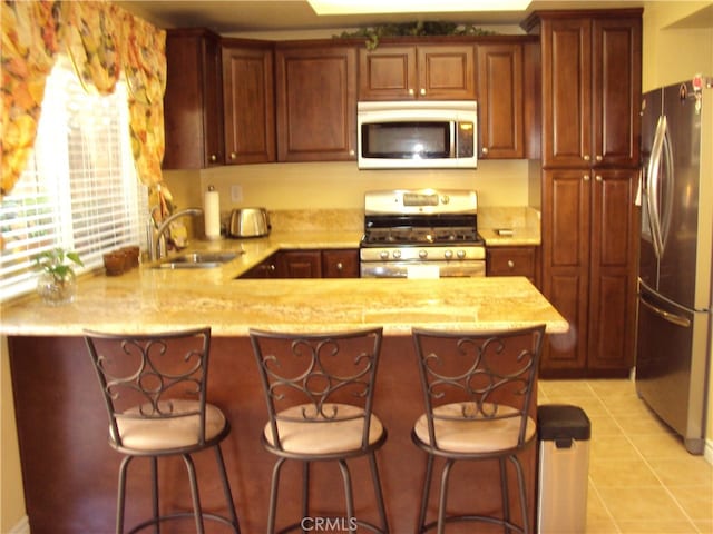 kitchen featuring sink, kitchen peninsula, stainless steel appliances, light stone counters, and light tile patterned floors