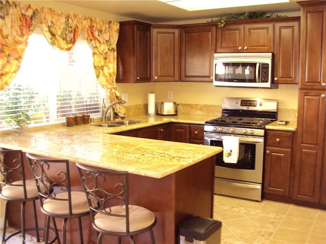 kitchen with sink, appliances with stainless steel finishes, a kitchen bar, and kitchen peninsula