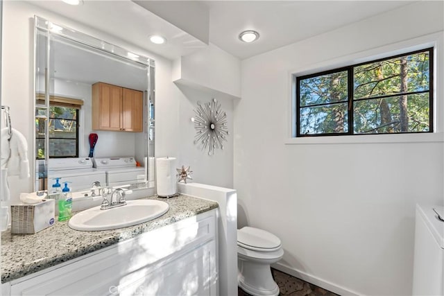 bathroom featuring vanity, toilet, a wealth of natural light, and washing machine and clothes dryer