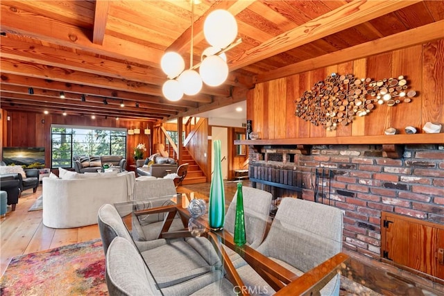 309 Castle Gate Rd, Lake Arrowhead, CA 92352 - dining room featuring a brick fireplace, stairway, a wood ceiling with exposed beams, wood walls, and hardwood / wood-style flooring