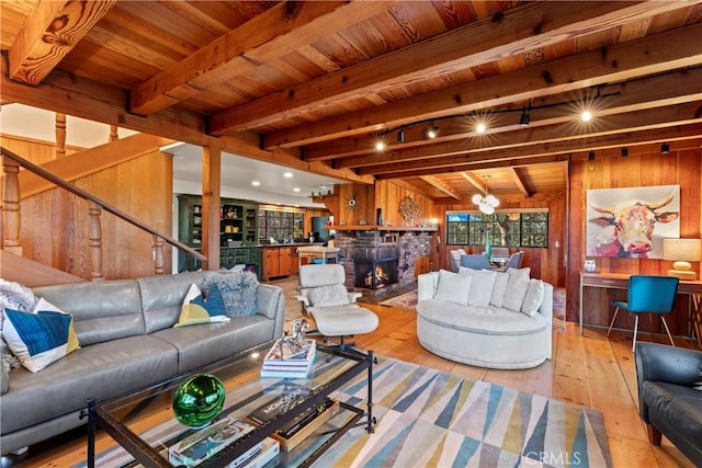 living room featuring wood walls, beam ceiling, wooden ceiling, and light hardwood / wood-style flooring