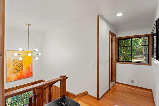 corridor with an inviting chandelier and light hardwood / wood-style flooring