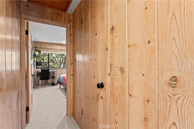 hallway featuring carpet floors and wood walls