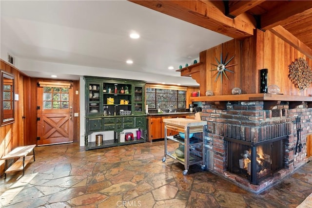 bar featuring beamed ceiling, wooden walls, and a brick fireplace