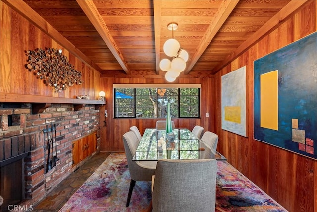 dining space with beam ceiling, a brick fireplace, wood walls, and wood ceiling