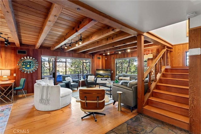 living room with beamed ceiling, light wood-type flooring, wooden ceiling, and wood walls