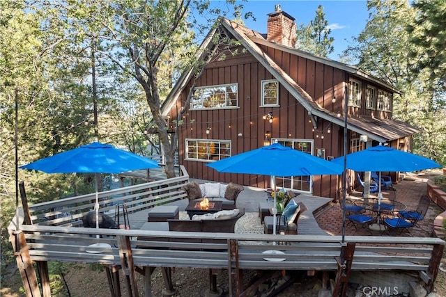 back of property featuring a wooden deck and an outdoor living space with a fire pit