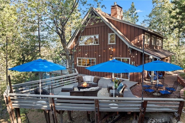 309 Castle Gate Rd, Lake Arrowhead, CA 92352 - back of property with a wooden deck, a chimney, outdoor dining space, and an outdoor living space with a fire pit