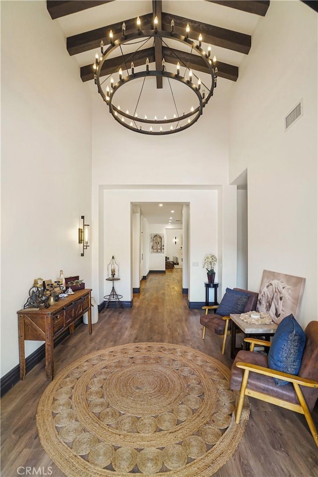 hall with beam ceiling, wood finished floors, and a towering ceiling