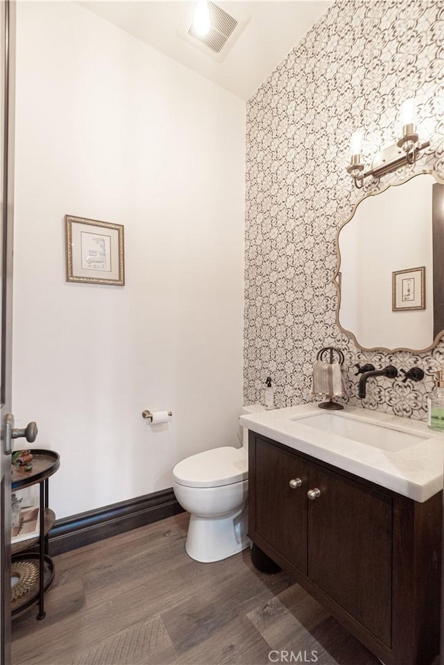 bathroom with toilet, visible vents, wood finished floors, and vanity
