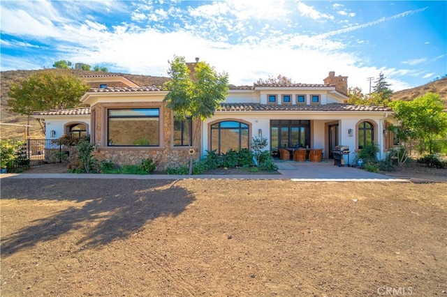 back of property featuring fence, a chimney, a tile roof, and stucco siding