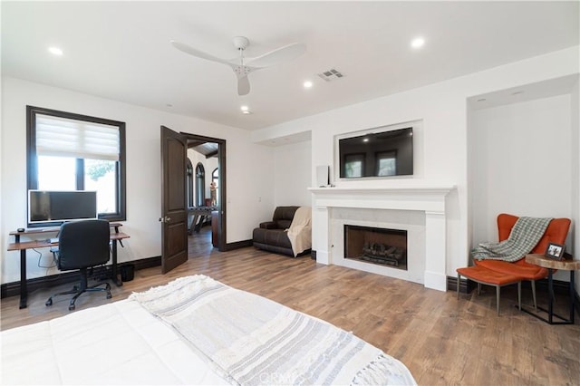 bedroom featuring a fireplace, recessed lighting, a ceiling fan, wood finished floors, and visible vents