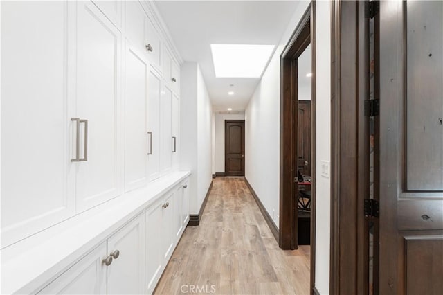 hallway featuring light hardwood / wood-style flooring and a skylight