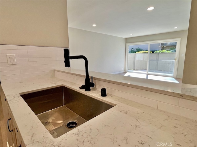 kitchen with sink, light stone counters, and backsplash