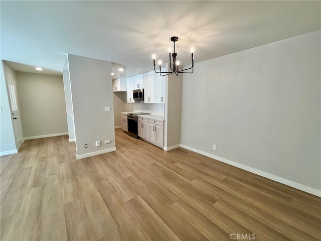 unfurnished living room with light hardwood / wood-style flooring and a chandelier