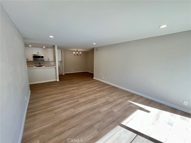 unfurnished living room with light hardwood / wood-style floors and an inviting chandelier