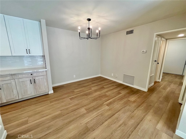 unfurnished dining area with light hardwood / wood-style flooring and an inviting chandelier