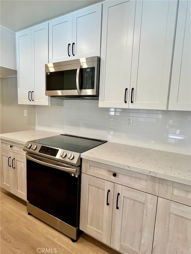 kitchen featuring light stone countertops, light hardwood / wood-style flooring, stainless steel appliances, and white cabinets