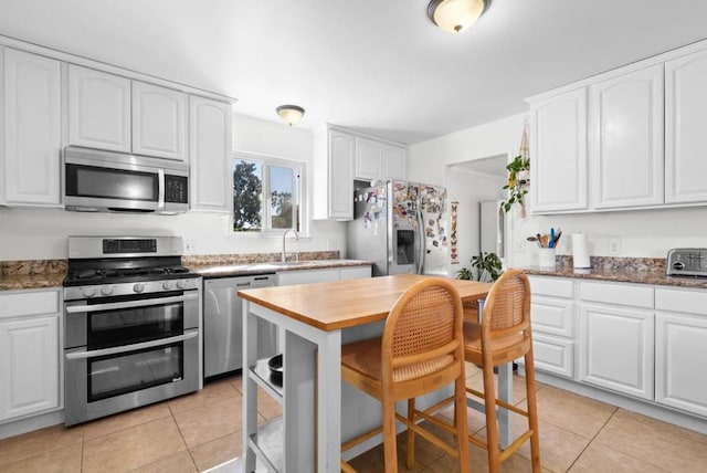 kitchen with appliances with stainless steel finishes, light tile patterned floors, and white cabinets