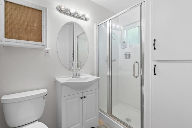 bathroom with vanity, toilet, and a shower with door