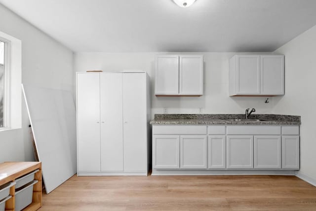 kitchen with white cabinetry, sink, and light wood-type flooring