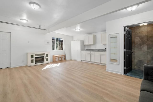 unfurnished living room featuring sink and light wood-type flooring