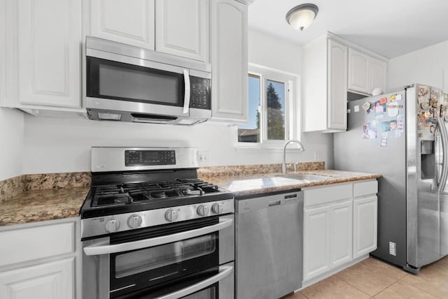 kitchen featuring sink, light tile patterned floors, stainless steel appliances, white cabinets, and stone countertops