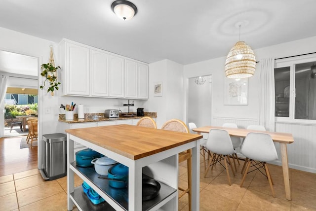 kitchen featuring white cabinetry, pendant lighting, wood counters, and light tile patterned floors