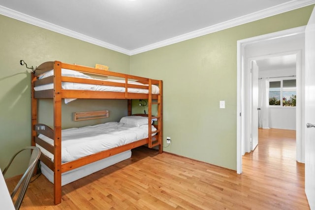 bedroom with ornamental molding and light hardwood / wood-style floors