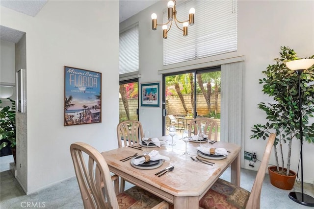 dining space featuring a towering ceiling, light colored carpet, and an inviting chandelier