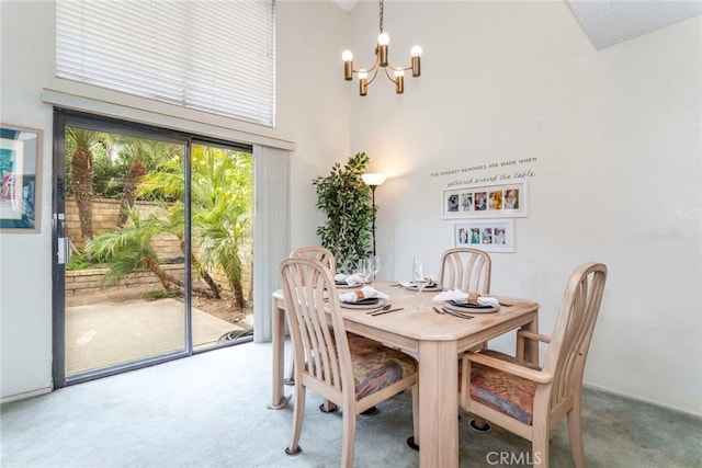 dining space with carpet floors, a towering ceiling, and an inviting chandelier